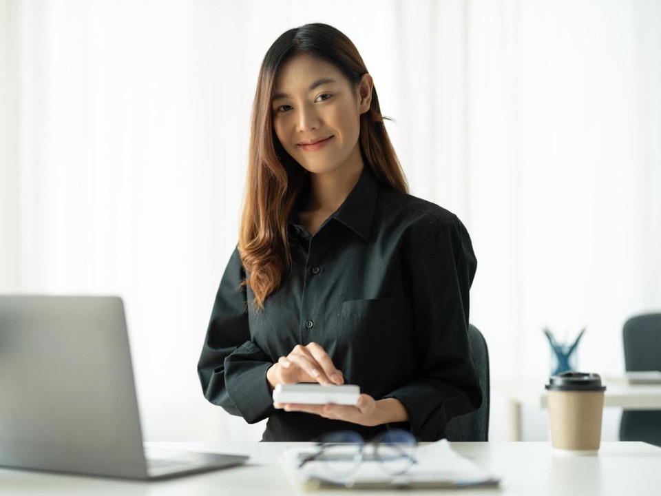 A consultant at a desk with a laptop, ledgers and a handheld calculator